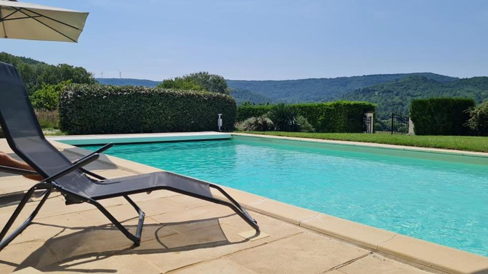 a chair and an umbrella next to a swimming pool at Les Genêts de la Valdaine in Rochefort-en-Valdaine