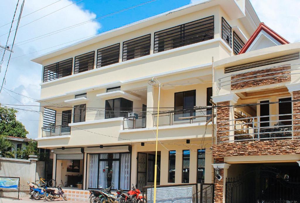 a white building with motorcycles parked in front of it at RedDoorz @ LS Suites Poblacion Culasi Antique in Jalandoni