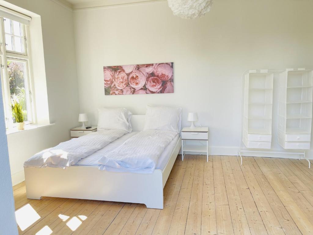 a white bedroom with a bed and a painting on the wall at aday - City Central Mansion - 1 Bedroom with big terrace in Aalborg