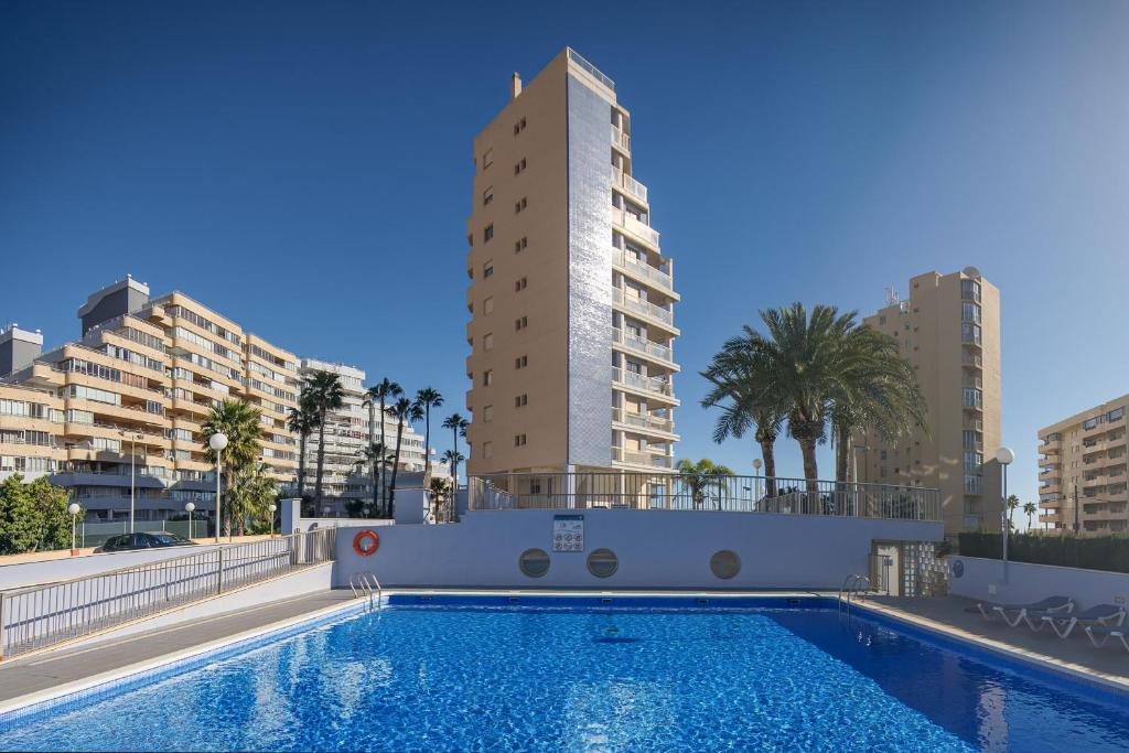 a swimming pool with two tall buildings in the background at Apartamentos Hipocampos Calpe Rent Apart in Calpe