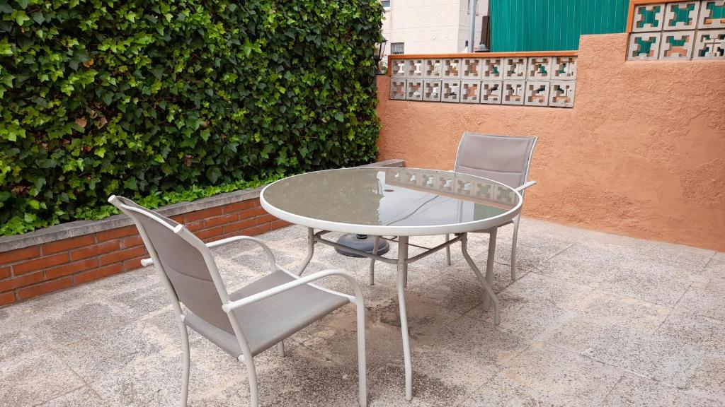 2 sillas y una mesa de cristal en el patio en Apartamento con piscina y bonita terraza, en Segur de Calafell