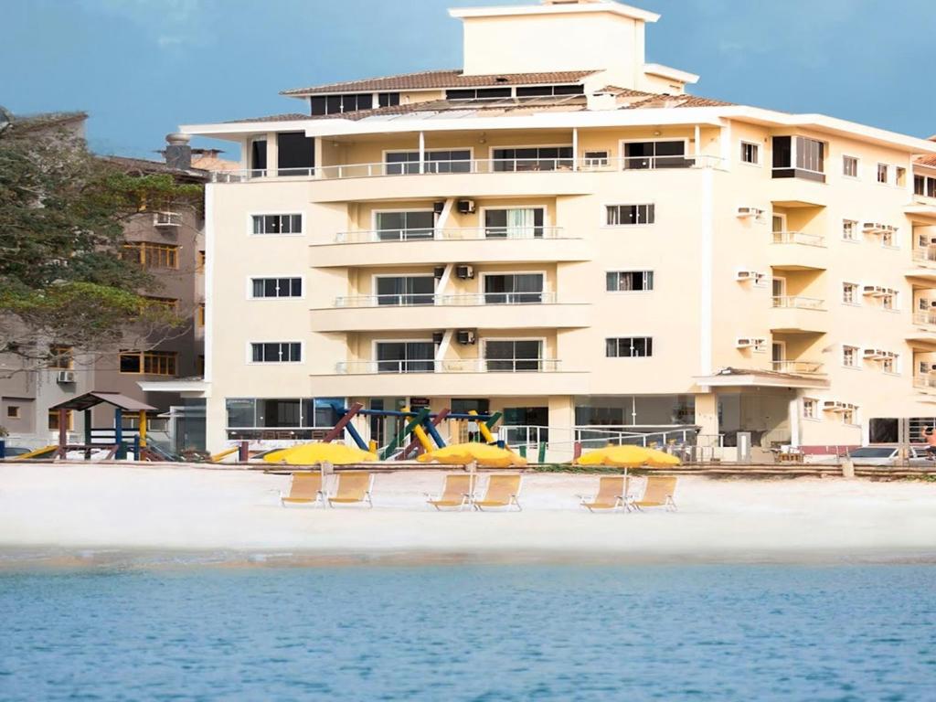 un hotel sulla spiaggia con sedie e ombrelloni di Hotel Monteiro Canasvieiras a Florianópolis