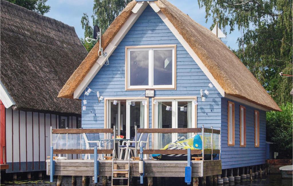 uma casa azul com um telhado de palha e duas cadeiras em Amazing Home In Mirow With Lake View em Mirow