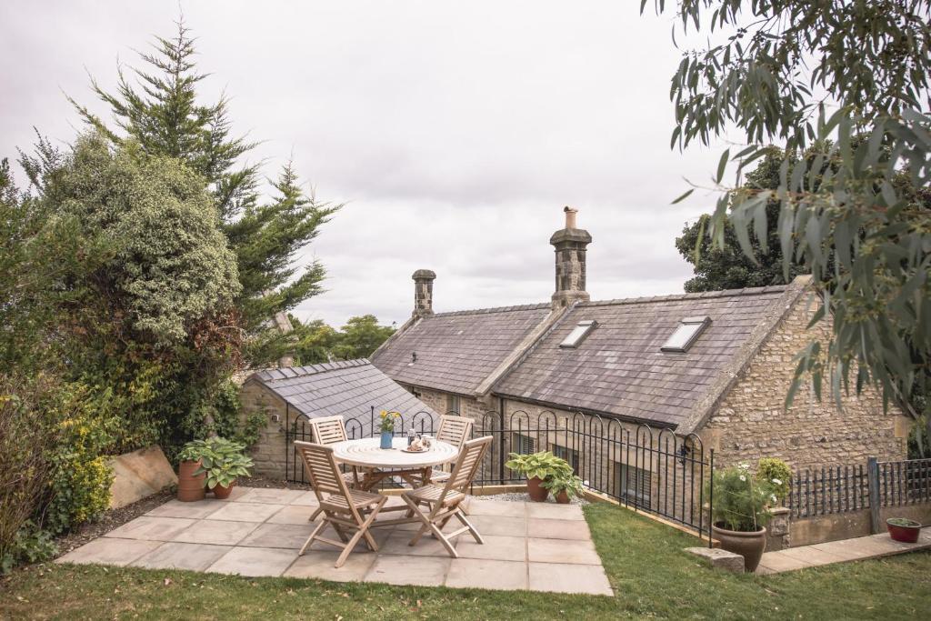 a patio with a table and chairs in front of a house at Poacher's Cottage in Leyburn