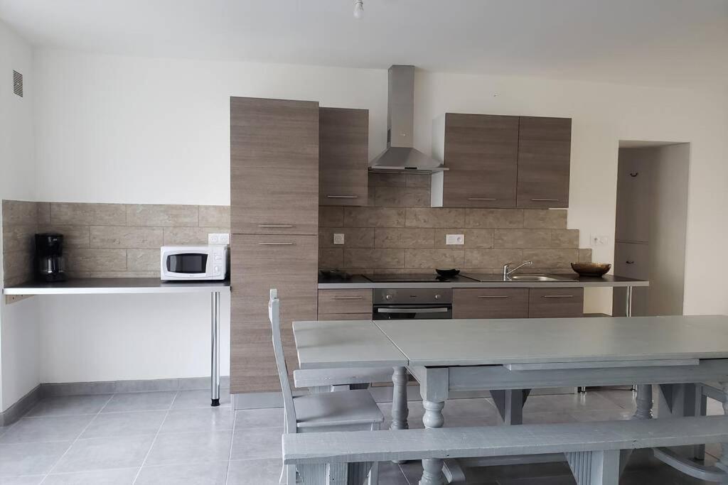 a kitchen with a table and a kitchen with a microwave at Maison chaleureuse avec parking gratuit sur place in Saint-Romain-sur-Cher