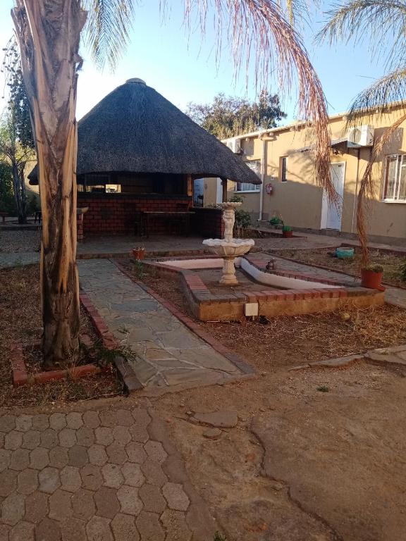 een gebouw met een rieten dak en een fontein bij Mongilo Guesthouse in Windhoek