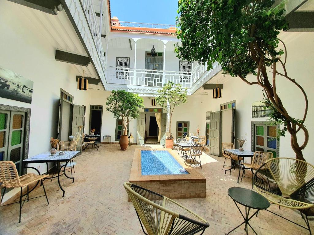 un patio con piscina, mesas y sillas en Riad Dar Zouar & Spa, en Marrakech