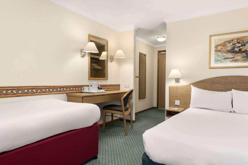 Una habitación de hotel con dos camas y un escritorio. en Days Inn by Wyndham Donington, en Castle Donington