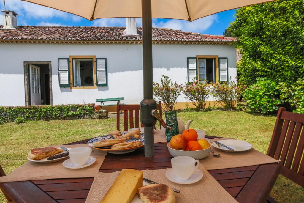 a wooden table with food on it with an umbrella at Domus Adepta Family w Garden in Furnas