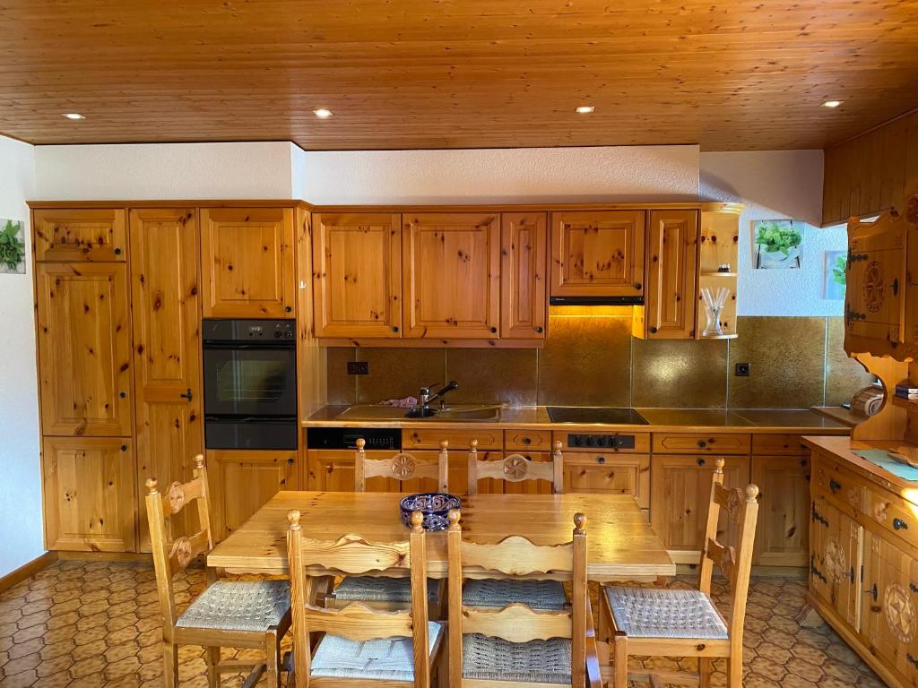 a kitchen with wooden cabinets and a wooden table with chairs at L'Arpille in Salvan