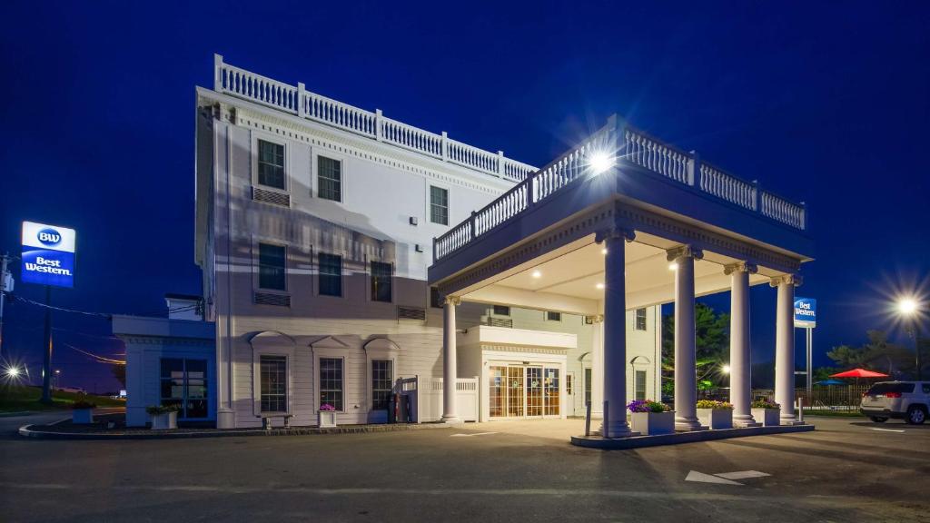 un gran edificio blanco con un aparcamiento iluminado en Best Western White House Inn, en Bangor