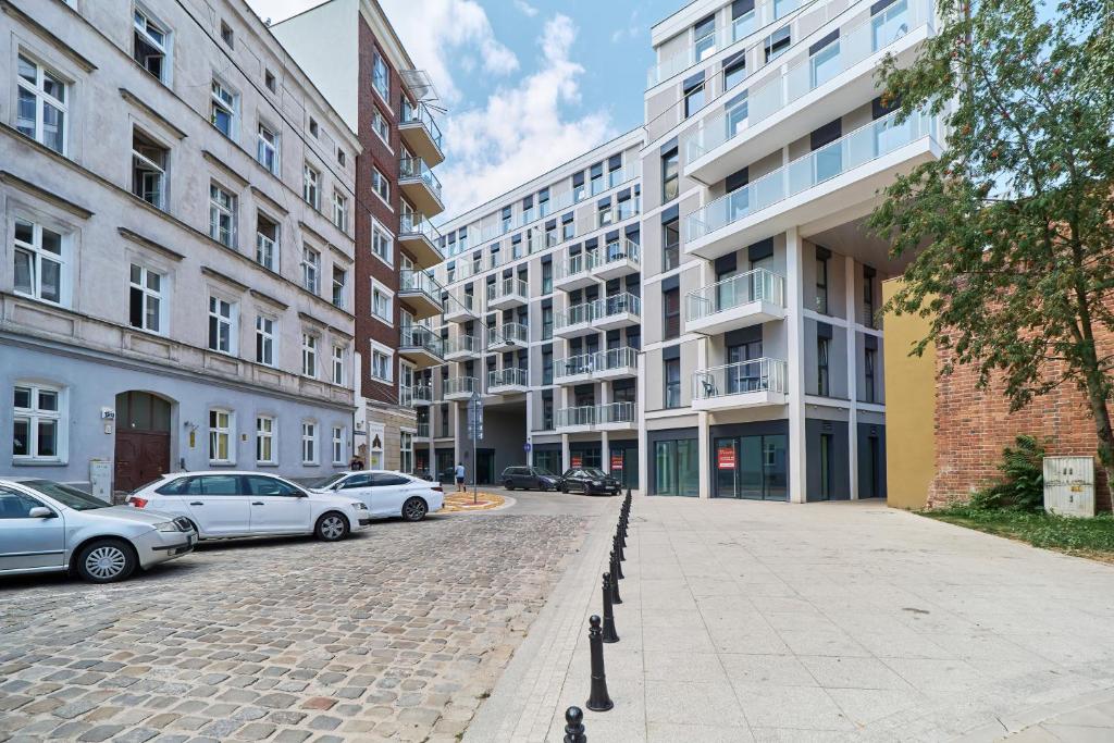brukowana ulica z samochodami zaparkowanymi przed budynkami w obiekcie Apartments Wrocław Jana Pawła II with FREE PARKING Wrocław by Noclegi Renters we Wrocławiu