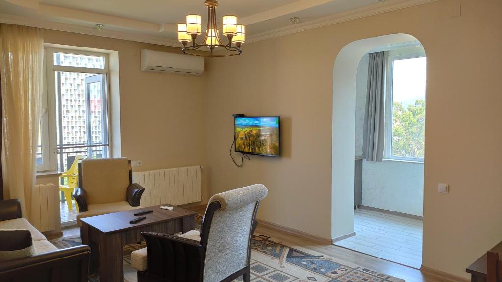 ein Wohnzimmer mit einem Tisch und Stühlen sowie einem TV in der Unterkunft Sea view apartment in Batumi