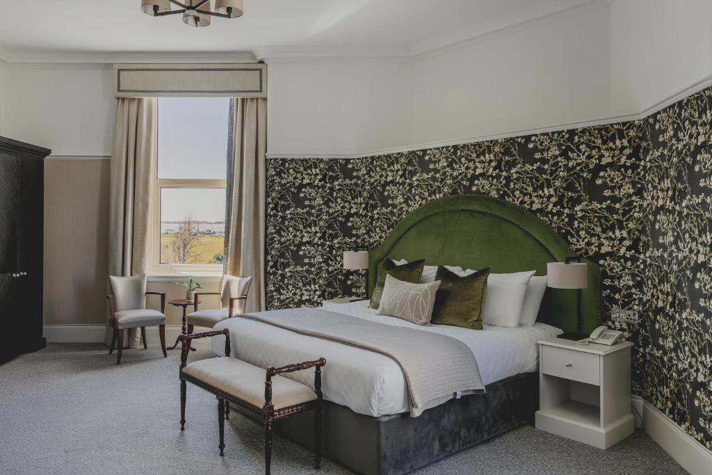 a bedroom with a large bed with a green headboard at The Queens Hotel in Portsmouth