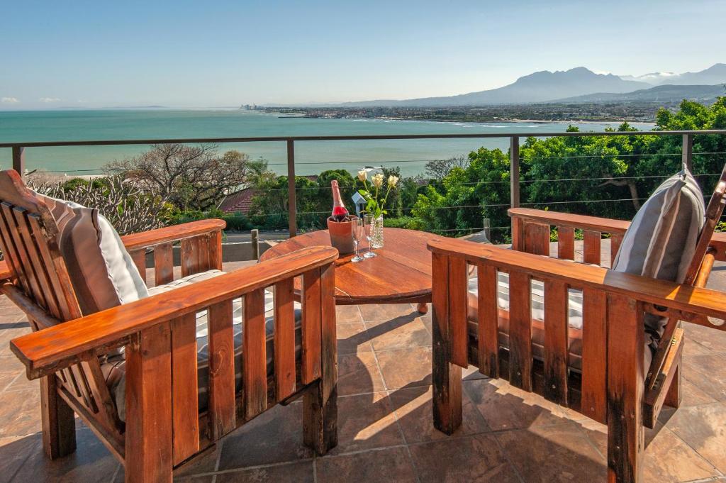 a patio with two benches and a table with a view at 18 On Kloof Guest House in Gordonʼs Bay