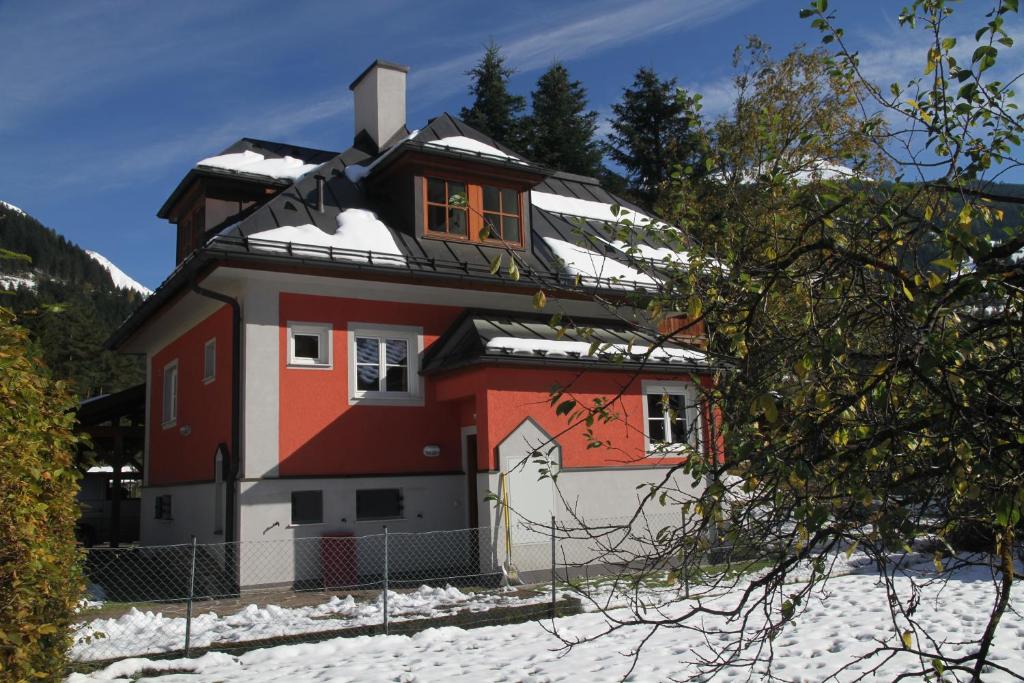 Una casa con nieve en el techo. en Villa Schnuck - das rote Ferienhaus, en Bad Gastein