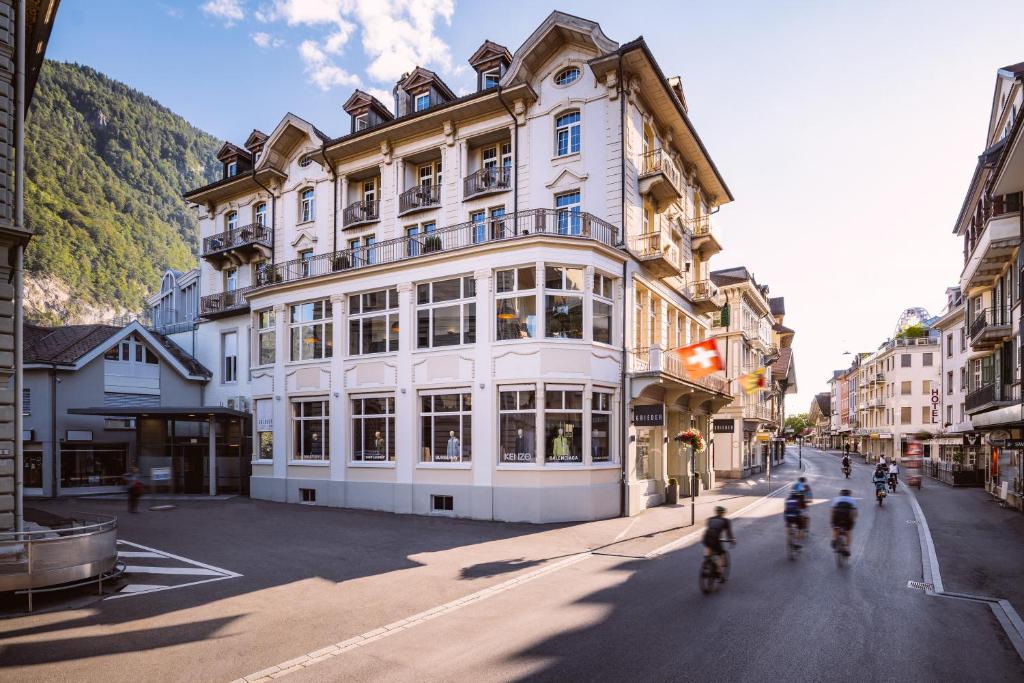 a group of people riding bikes down a street in front of a building at The HEY HOTEL in Interlaken