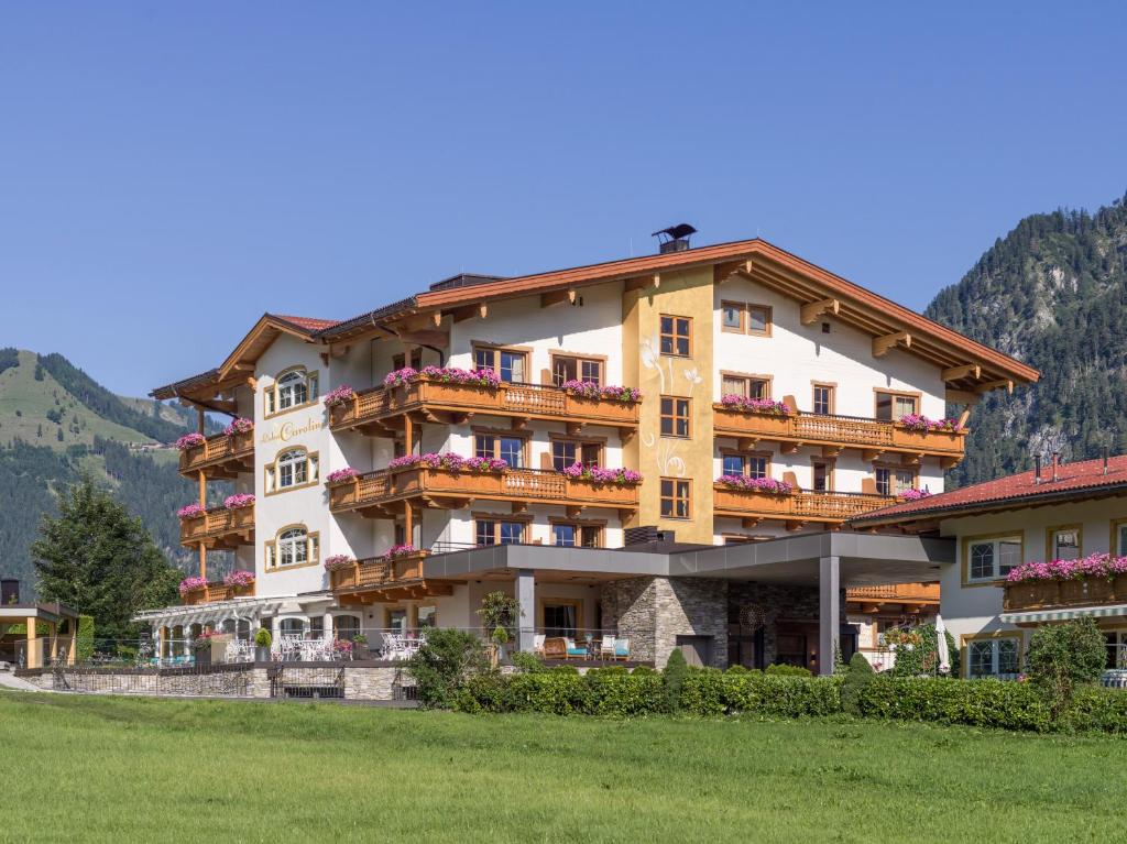 a large building with flowers on the balconies of it at Liebes Caroline 4-Sterne-Hotel in Pertisau