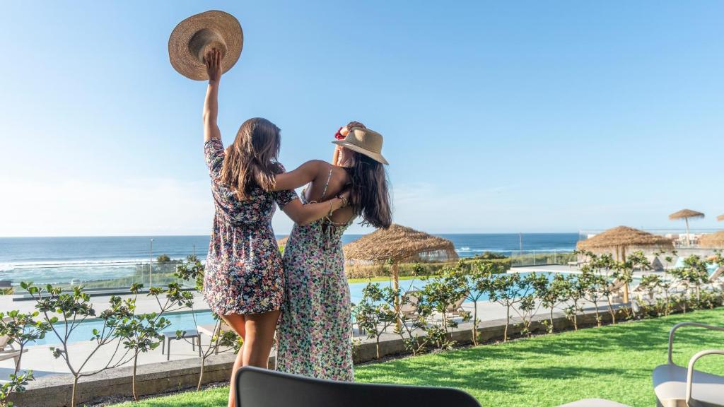 two girls standing next to a pool at a resort at Hotel Verde Mar & SPA in Ribeira Grande