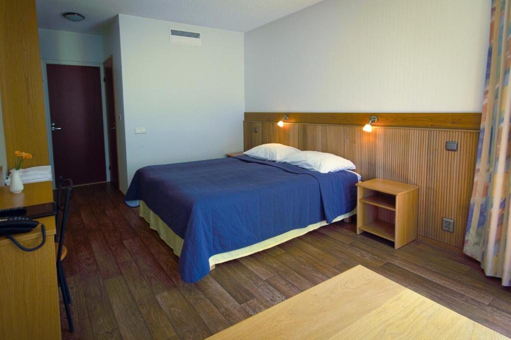 a bedroom with a blue bed and a wooden floor at Hotelli Pesti in Parkano