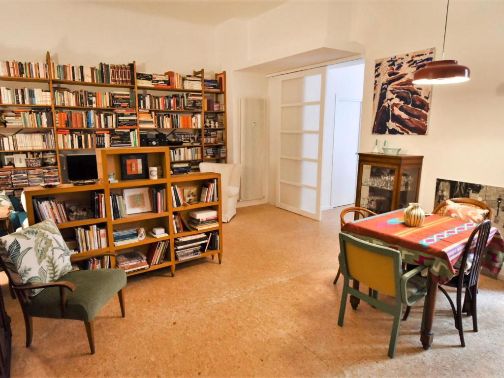 ein Wohnzimmer mit einem Tisch, Stühlen und Bücherregalen in der Unterkunft Apartment NoLo Art Apartment by Interhome in Mailand