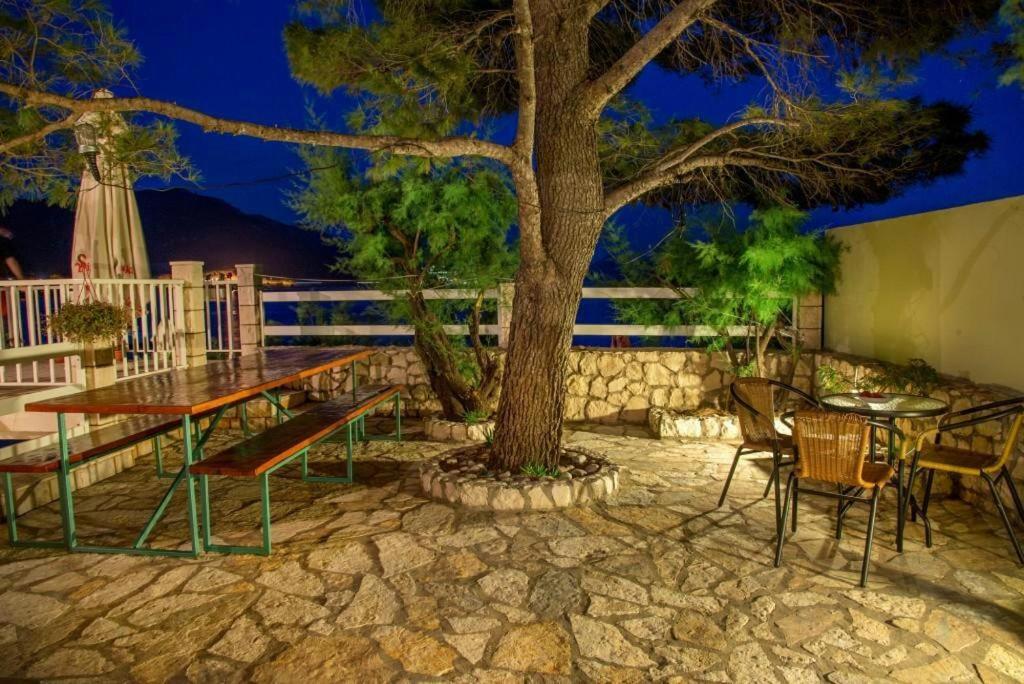 a patio with a table and chairs and a tree at Apartments Krstičević in Klek