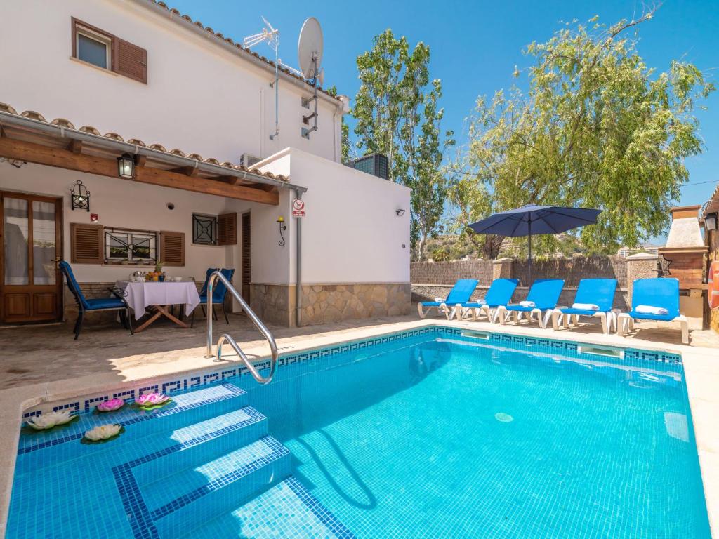 a swimming pool with chairs and an umbrella next to a house at Holiday Home Pintor Beach House by Interhome in Port de Pollensa