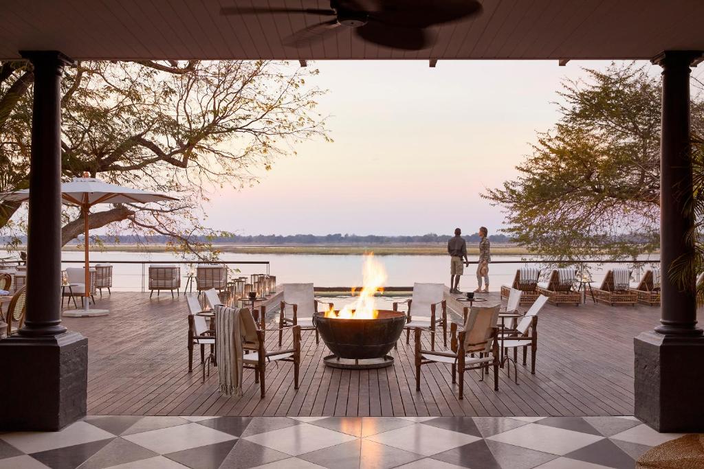 a fire pit on a deck with tables and chairs at Zambezi Grande Private Game Experience in Mafuta