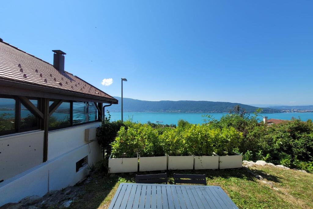 een huis met een tafel en uitzicht op het water bij Maisonnette vue panoramique lac d'Annecy in Veyrier-du-Lac