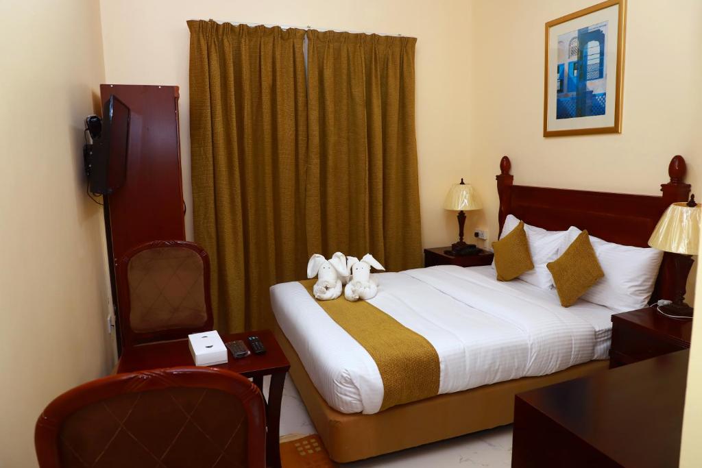 Onyx Hotel Apartments - MAHA HOSPITALITY GROUP في عجمان: غرفة فندق عليها سرير يوجد عليها حيوانات محشوة