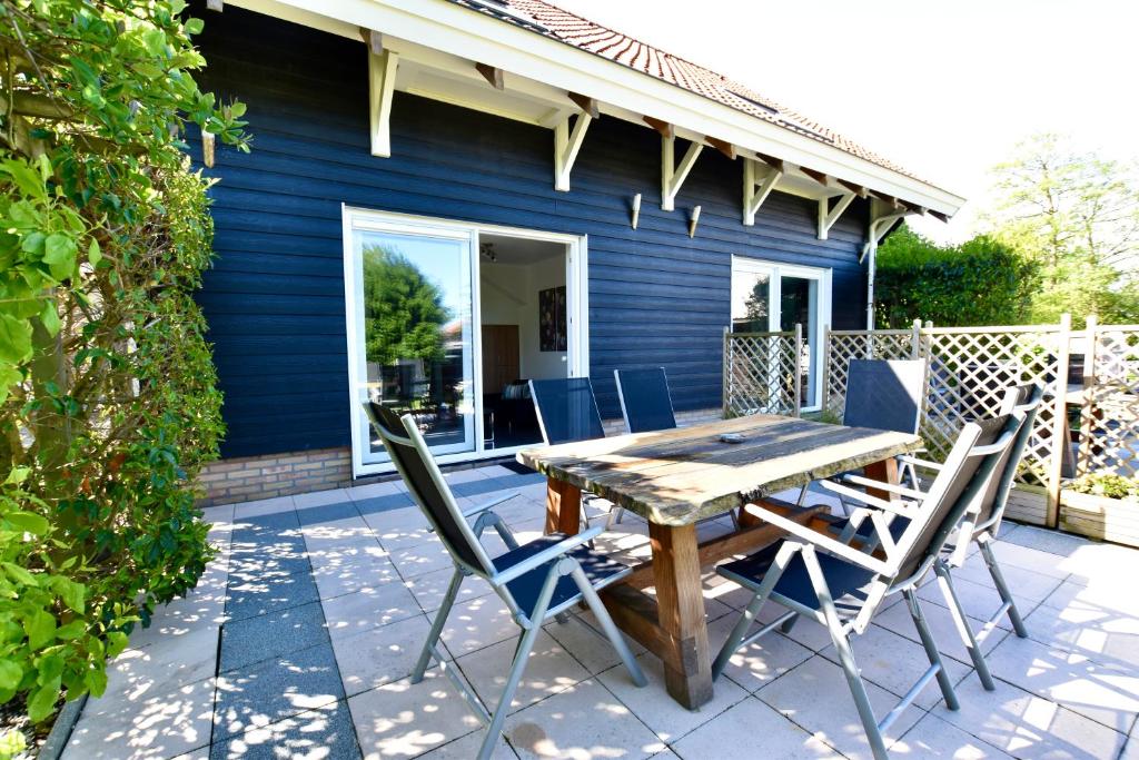 un patio con mesa de madera y sillas en Resort De Vlasschure, en Wissenkerke