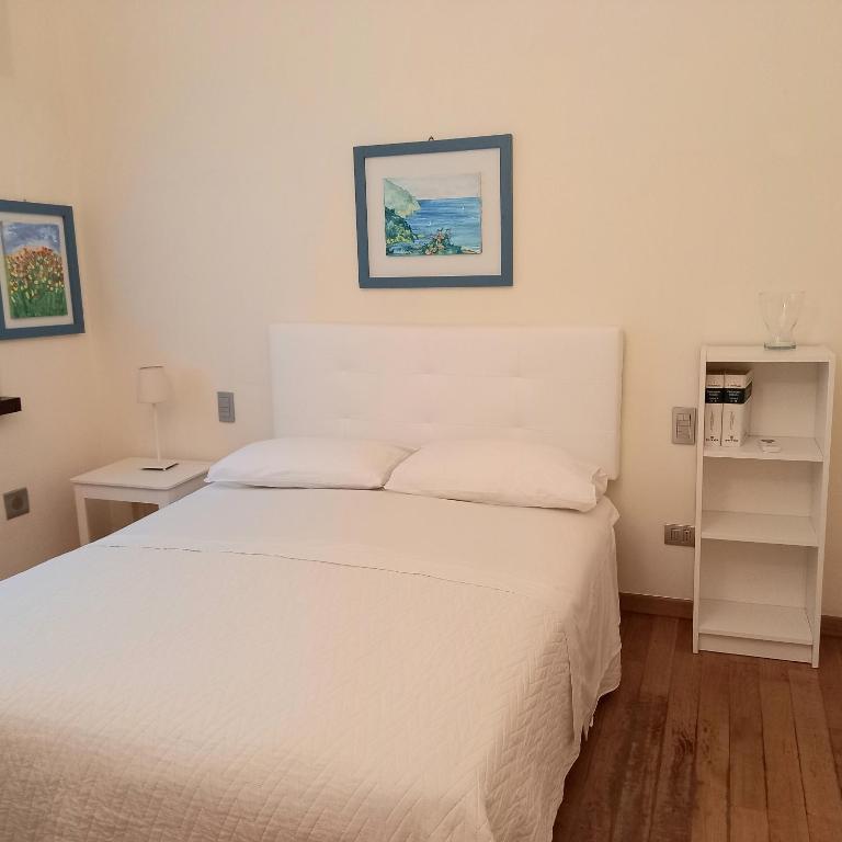 sypialnia z białym łóżkiem i półką w obiekcie Giardino delle rose w mieście Lido di Fermo