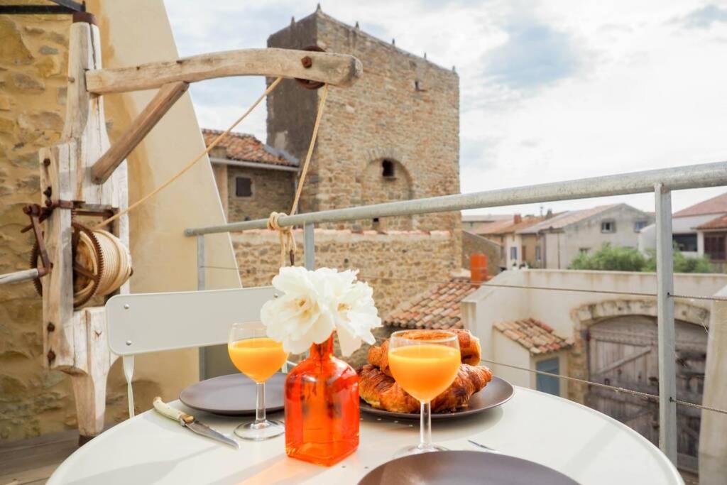 a table with two glasses of orange juice on a balcony at La Porte du Midi in Mailhac