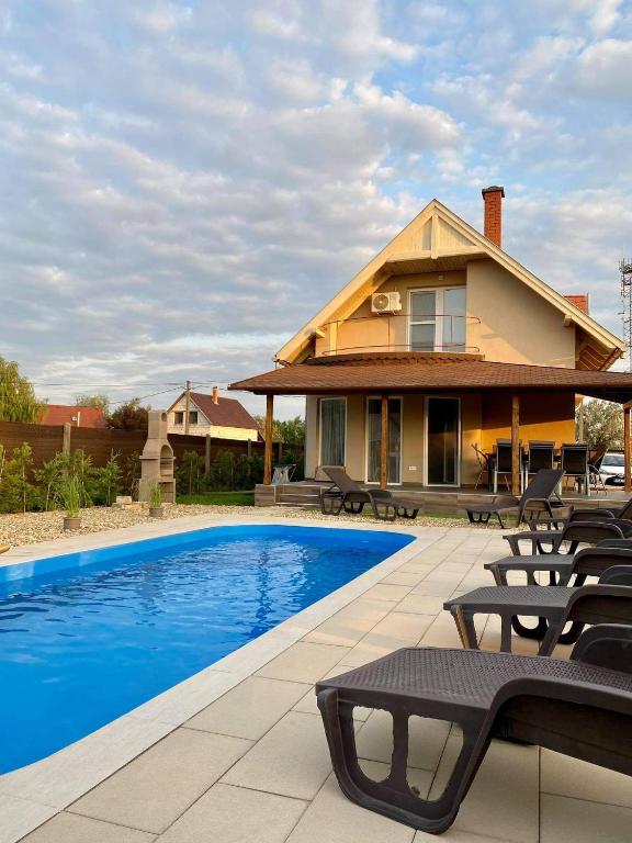 a house with a swimming pool in front of a house at Tiszavirág Üdülőház in Kisköre
