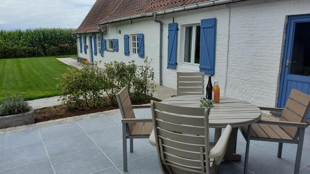 een houten tafel en stoelen op een patio bij Au Chant des Oiseaux in Tournai