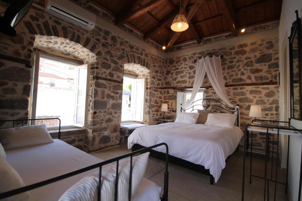 a bedroom with two beds in a room with stone walls at Guesthouse Alexandra in Hydra