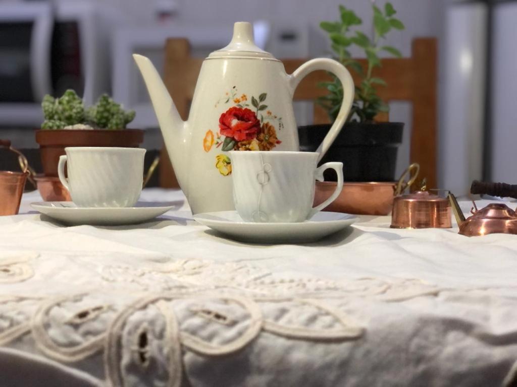 a tea pot and two cups on a table at Bela Vista - Casa inteira in Tiradentes