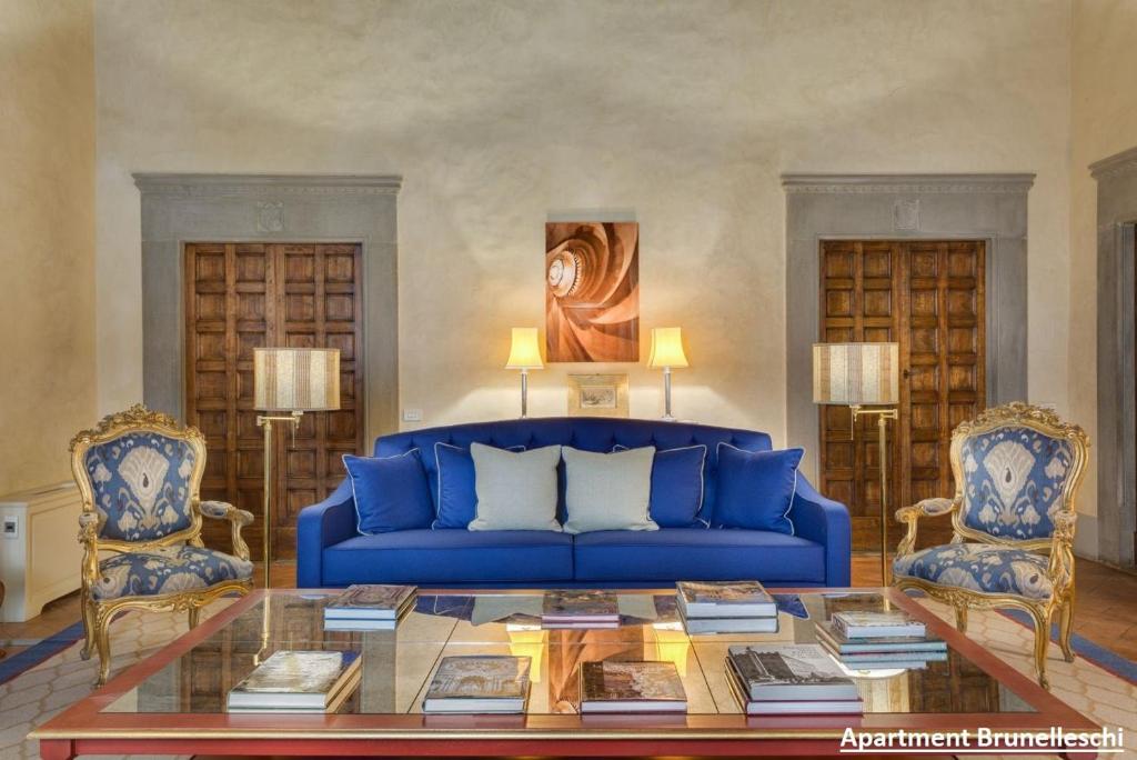 a living room with a blue couch and two chairs at Palazzo Salviati by Varental in Florence