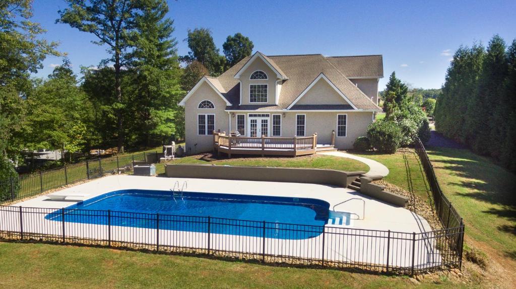 a house with a swimming pool in front of a house at Mountain Shadows BRAND NEW Luxurious House with Heated Pool - Games - And More Near Asheville! in Leicester