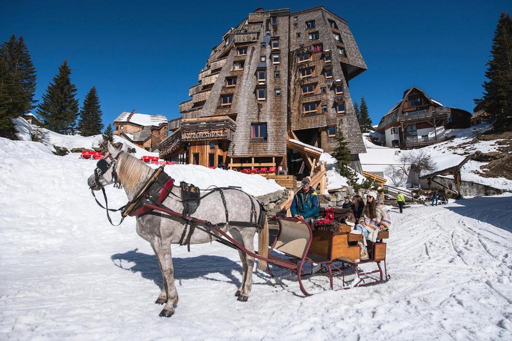 a horse pulling a sleigh in front of a building at Hôtel des Dromonts by SOWELL COLLECTION in Avoriaz