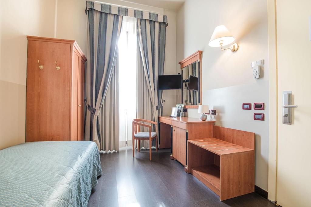 a bedroom with a bed and a desk and a window at Hotel Impero in Cremona