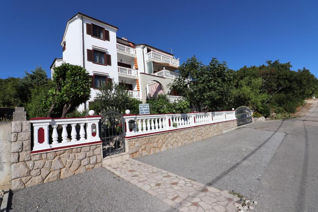 un edificio blanco en una pared de piedra junto a una calle en Villa Sojat, en Crikvenica