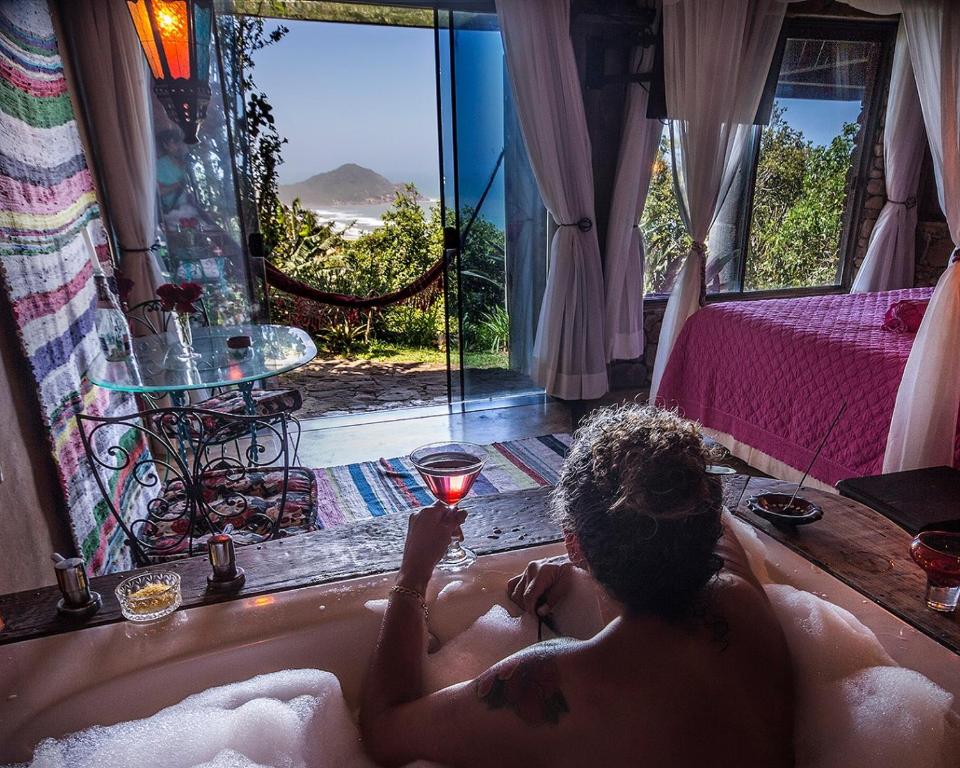 a man sitting in a bath tub with a candle at Villa Buena Vista in Praia do Rosa