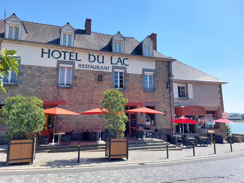 a hotel dmg with orange umbrellas in front of it at Hôtel Restaurant du Lac in Combourg