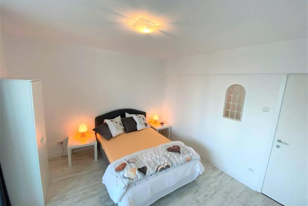 een slaapkamer met een bed en 2 verlichting aan het plafond bij Perla Spacious 2 Bedroom Apartment in Boekarest