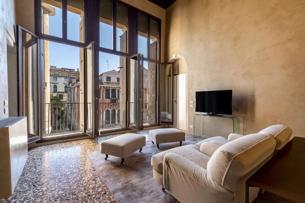 a living room with a couch and a tv and large windows at Portego del Drapier in Venice