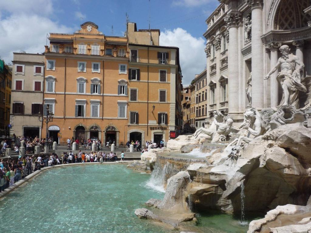 uma fonte numa cidade com pessoas à sua volta em Rental in Rome Trevi Fouintain View Apartment em Roma