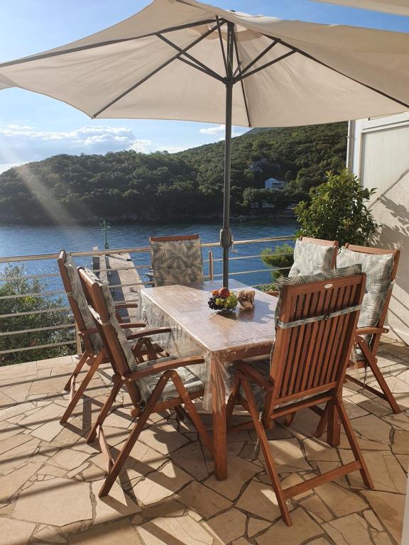 a wooden table and chairs with an umbrella on a patio at Kuća za odmor "TONI" in Kuna Pelješka