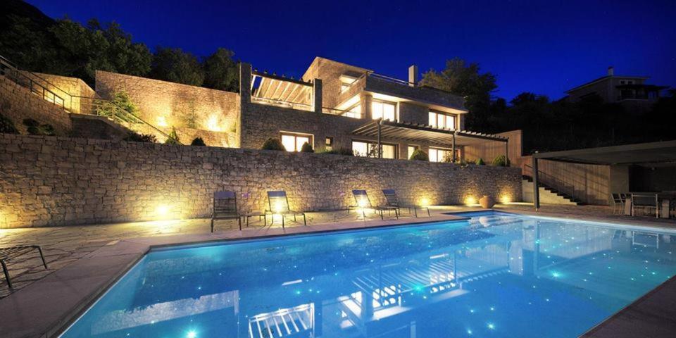 - une piscine en face d'une maison la nuit dans l'établissement Elafivolia Arachova Suites, à Arachova