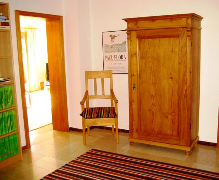a room with a chair and a wooden cabinet at Ferienwohnung Ebner in Kiefersfelden